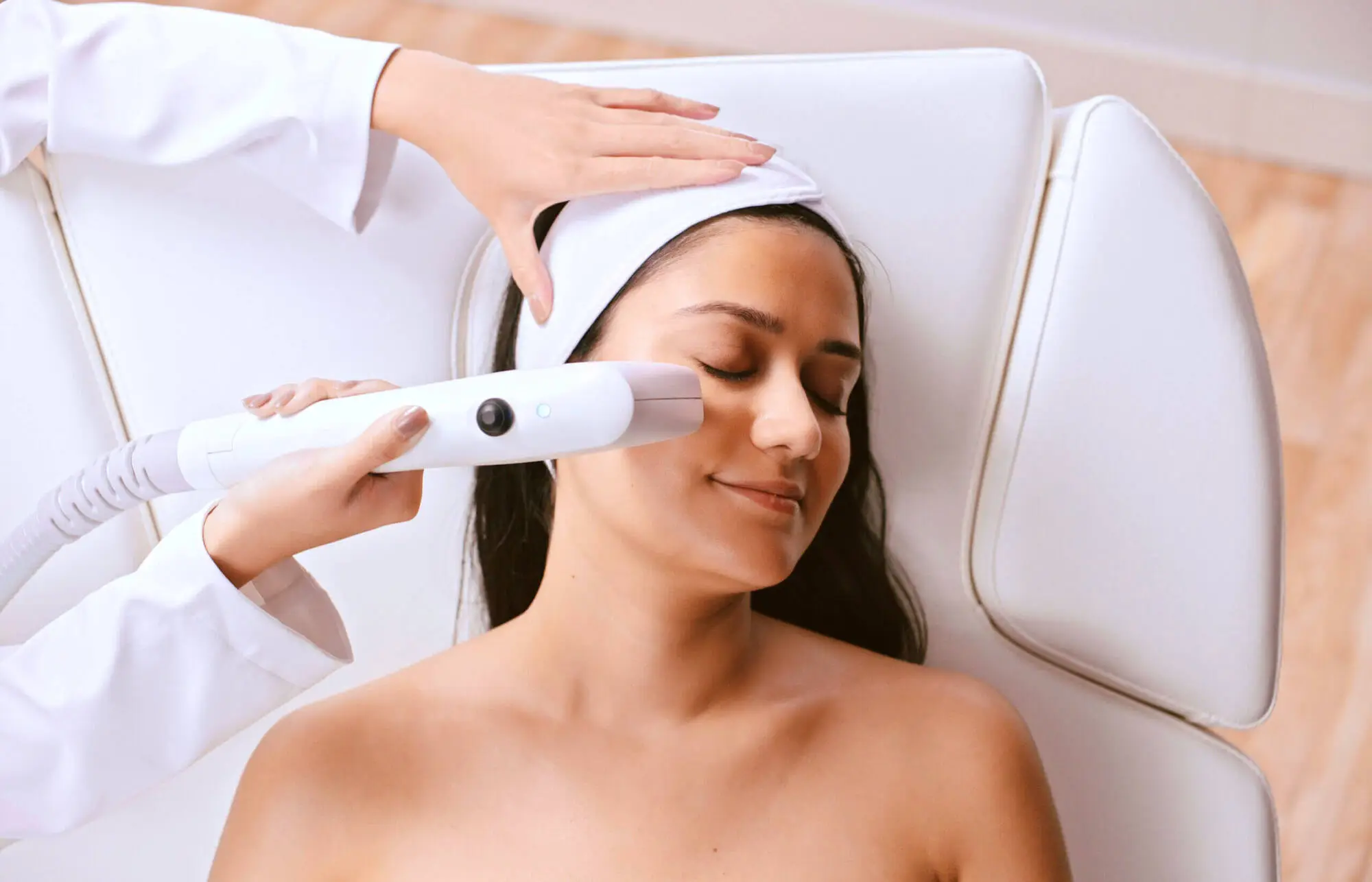 Practitioner applying Sofwave device to patient's cheek during aesthetic treatment