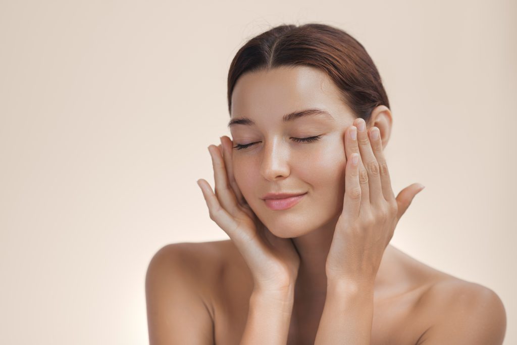 Woman with eyes closed, hands framing face, demonstrating lifted facial contours