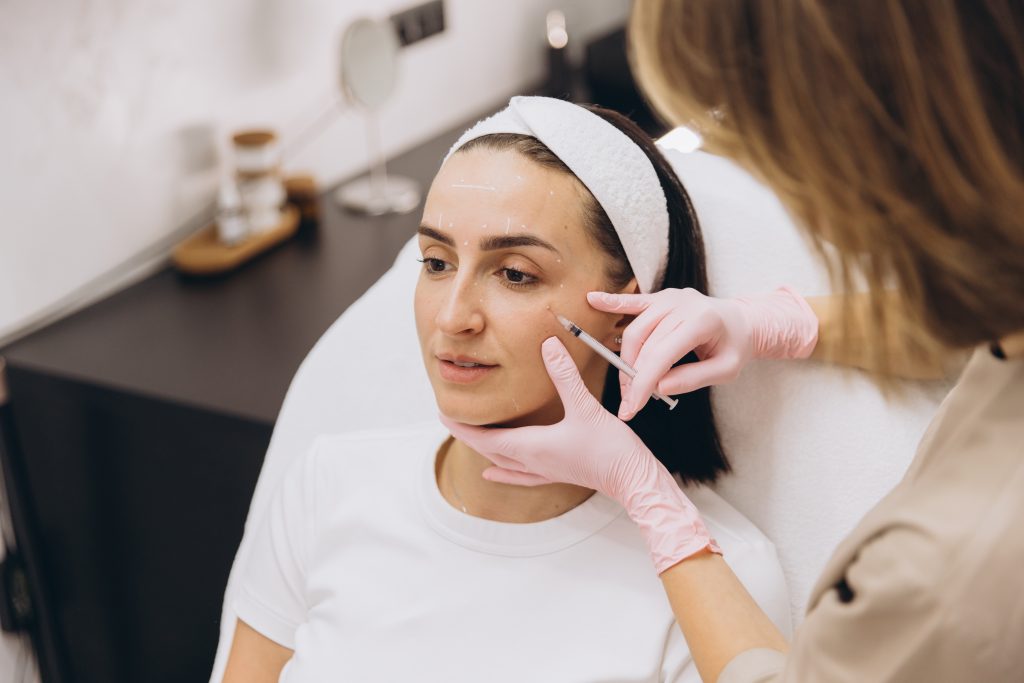 Provider in pink gloves examining patient's skin during aesthetic consultation in treatment room