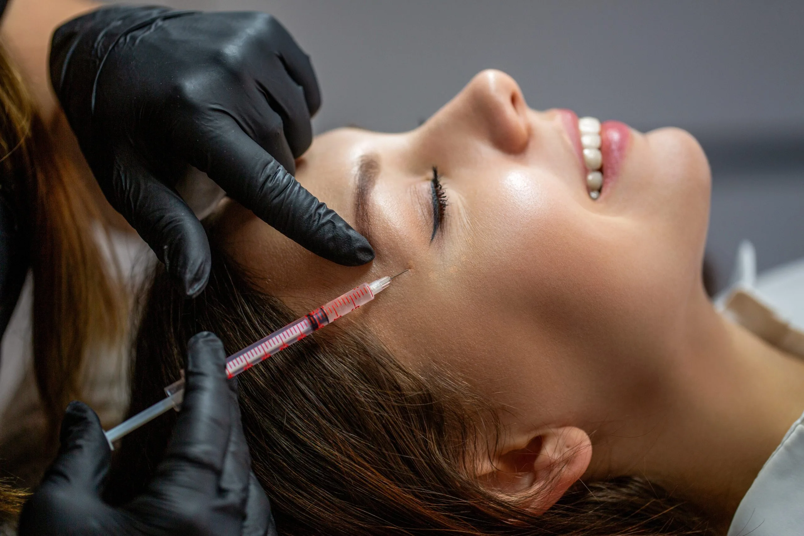 Woman receiving a Botox injection near the outer brow, dosed in units