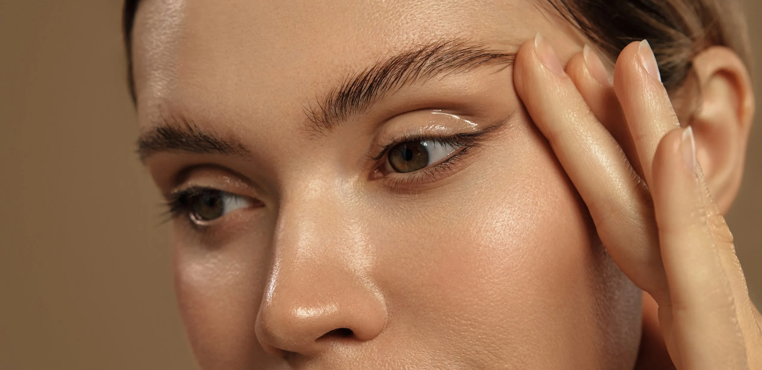Close-up of a woman's eye and smooth upper eyelid as she touches her temple